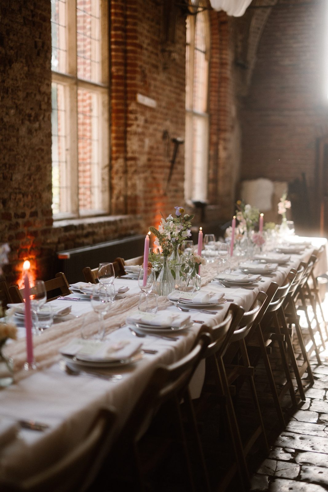 Lange dinertafel met roze kaarsen in een kloostergang