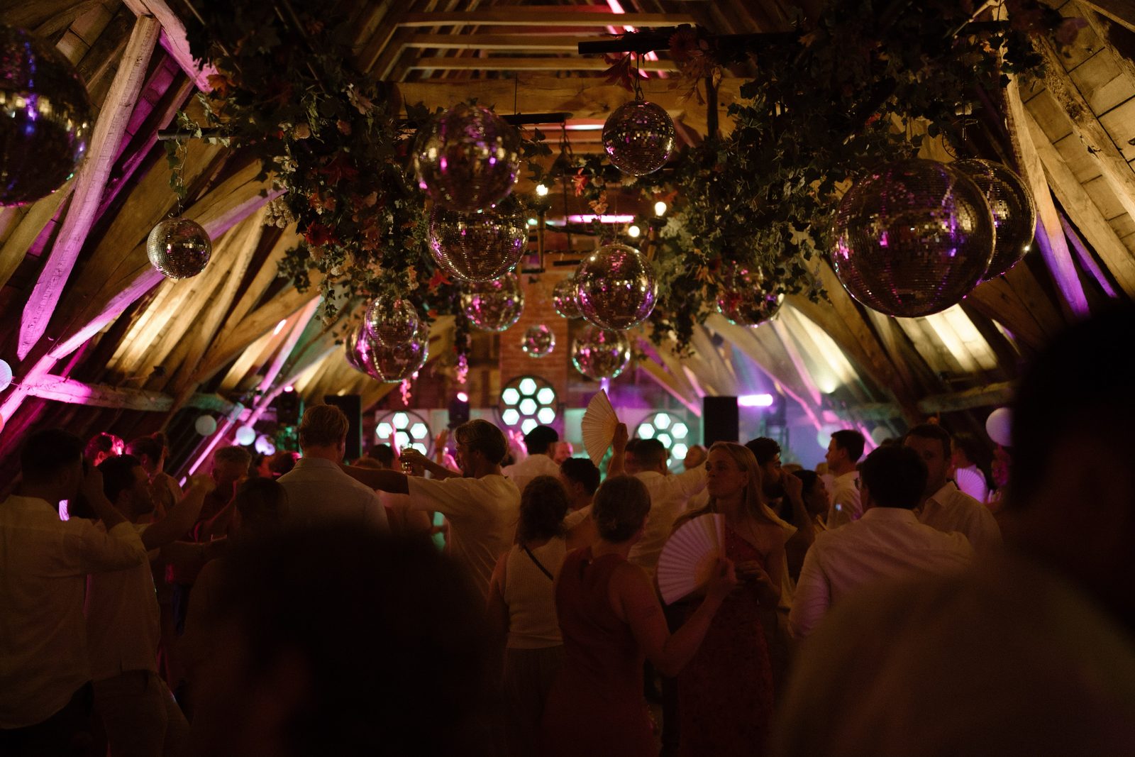 Dansende gasten onder een plafond vol discoballen en groen