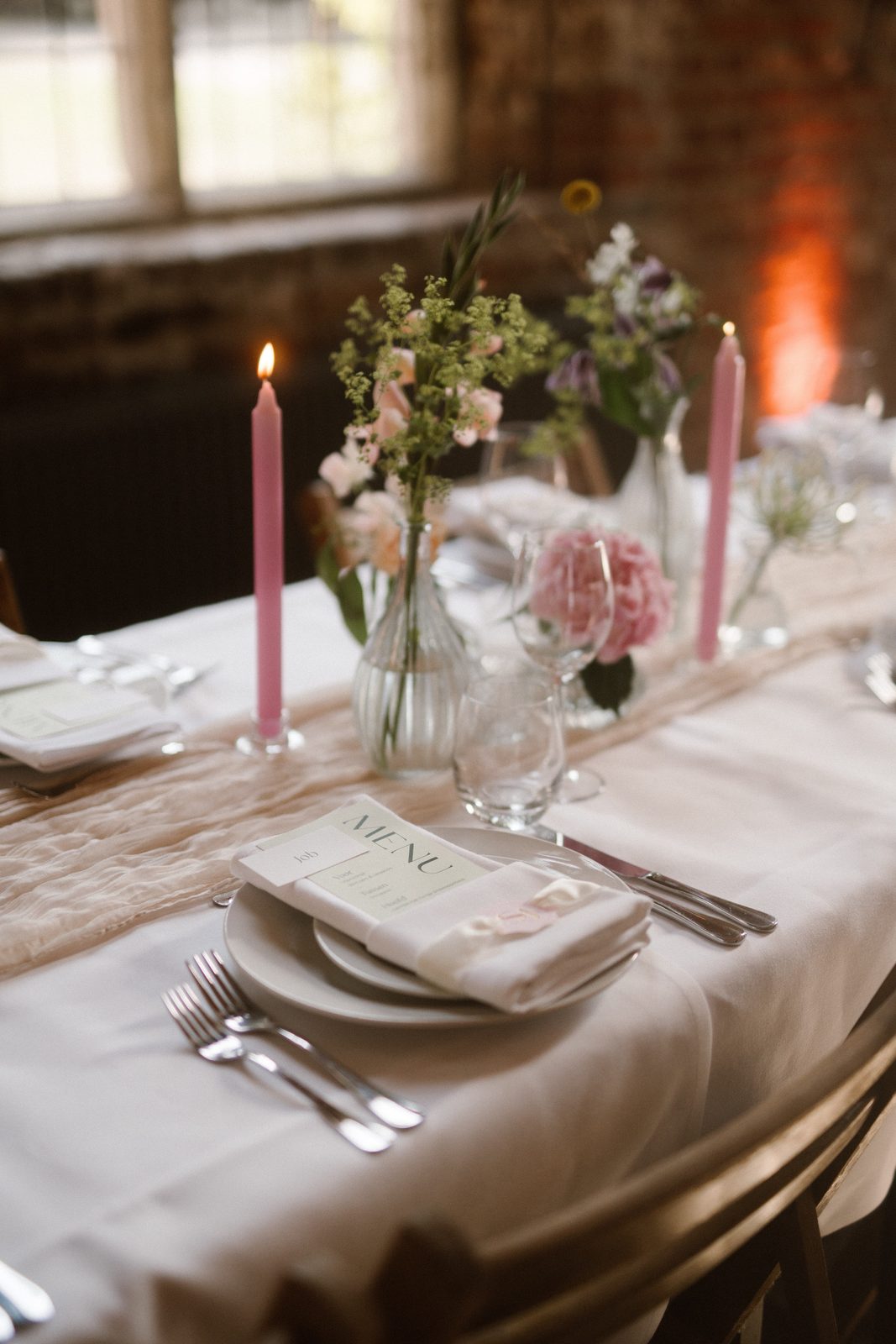 Tafelstyling met roze kaarsen, bloemen en een menukaart