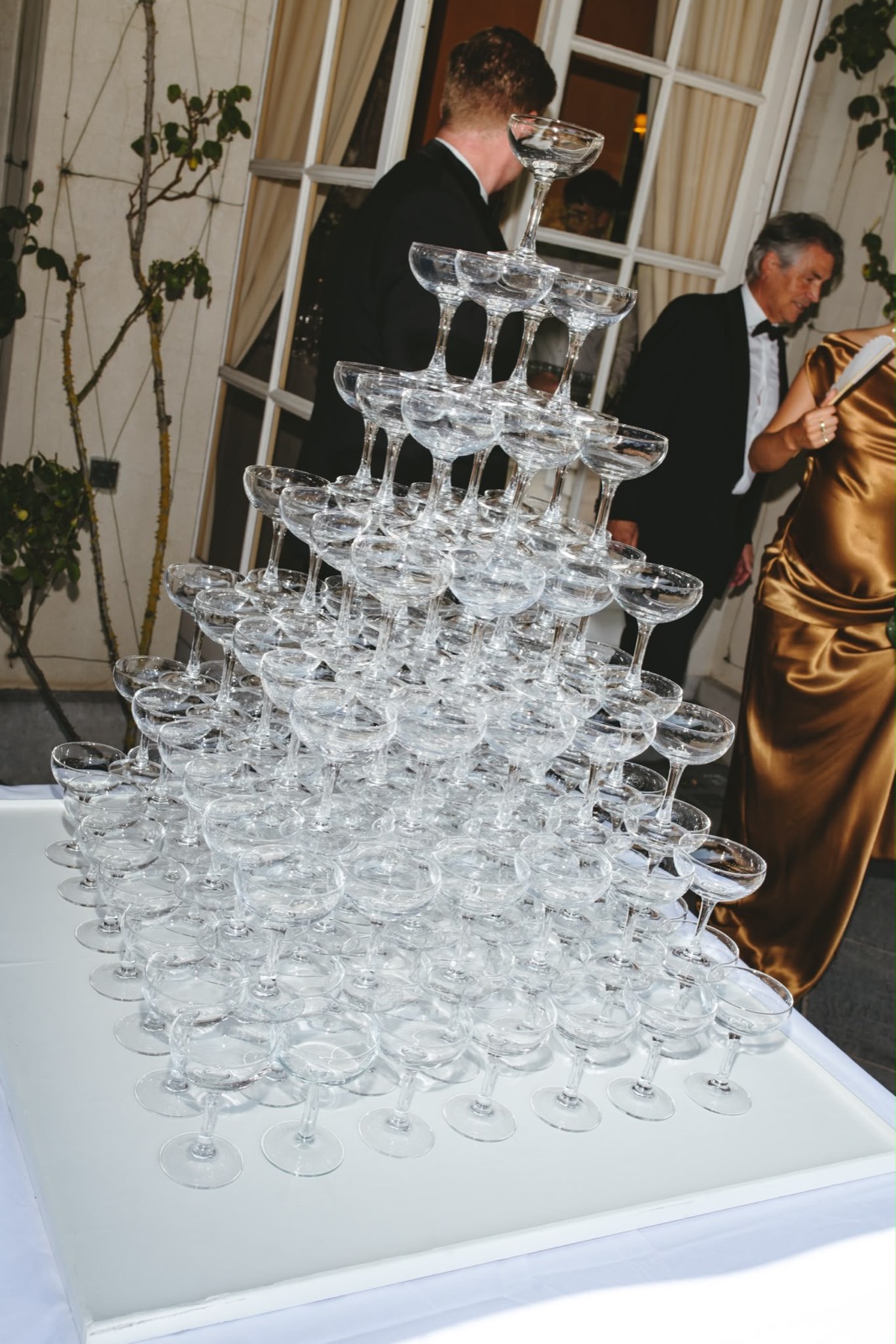 Champagnetoren van glazen op een tafel, gasten op de achtergrond