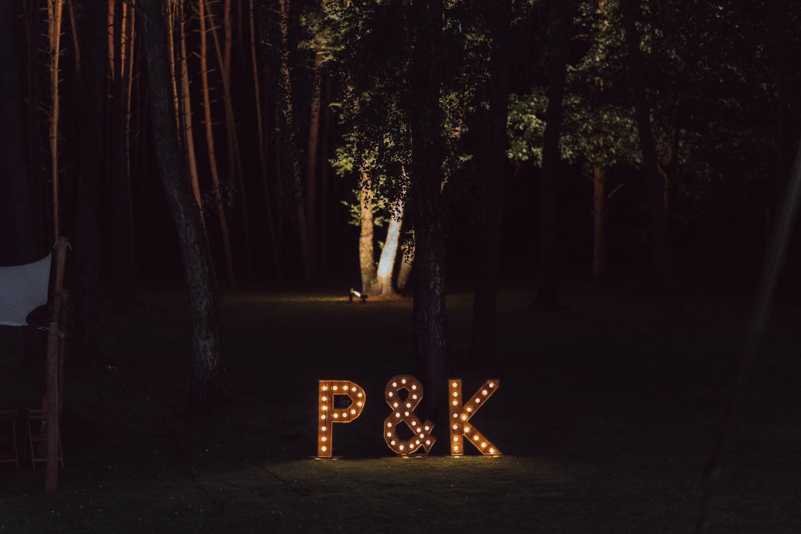 Verlichte letters P&K tussen de bomen in het donker