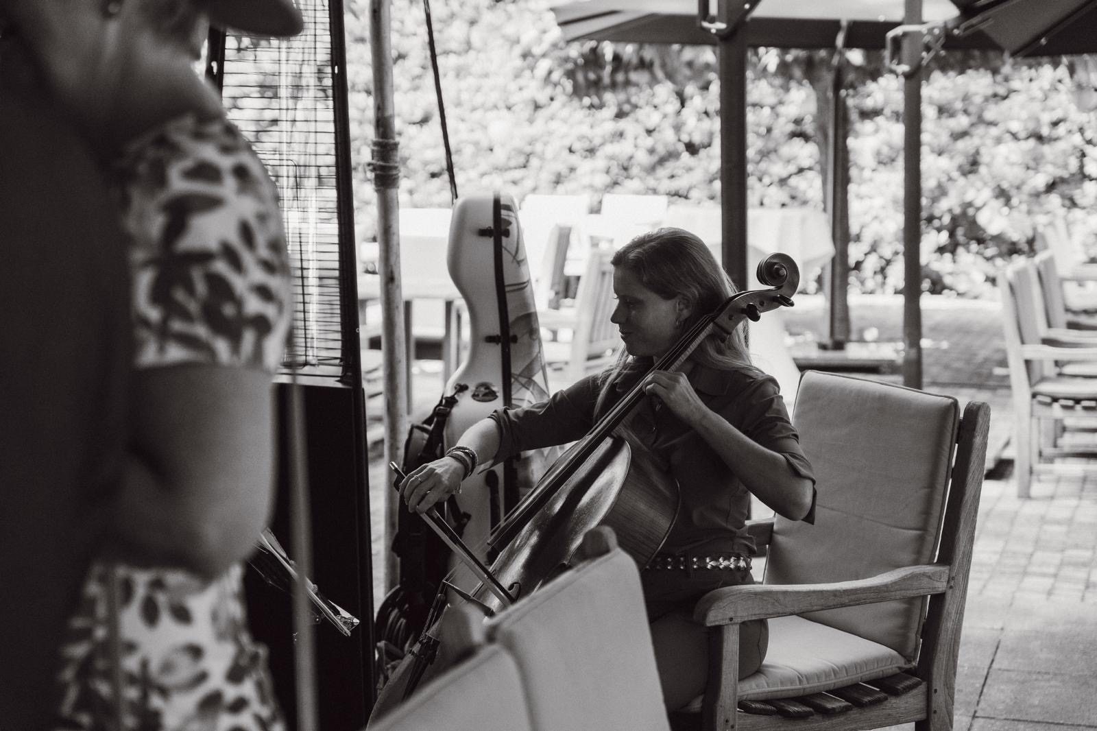 Celliste speelt tijdens de borrel, zwart-wit